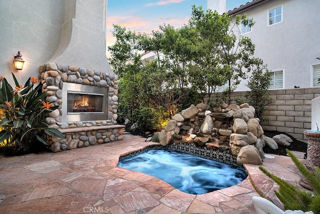 view of pool featuring an outdoor stone fireplace, an in ground hot tub, and a patio area