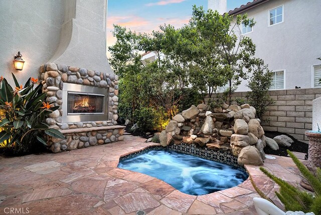 26238 Beecher Ln, Stevenson Ranch, CA 91381 - pool at dusk with an outdoor stone fireplace, an in-ground hot tub, and a patio area