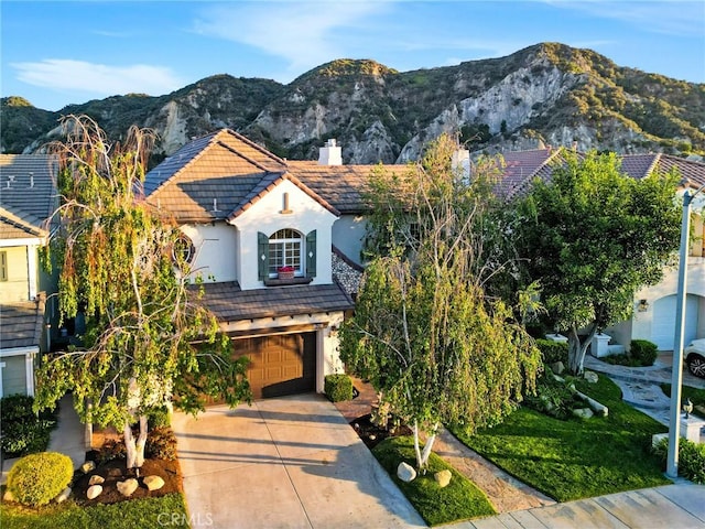 view of front of house with a garage, stucco siding, a chimney, a mountain view, and a tile roof