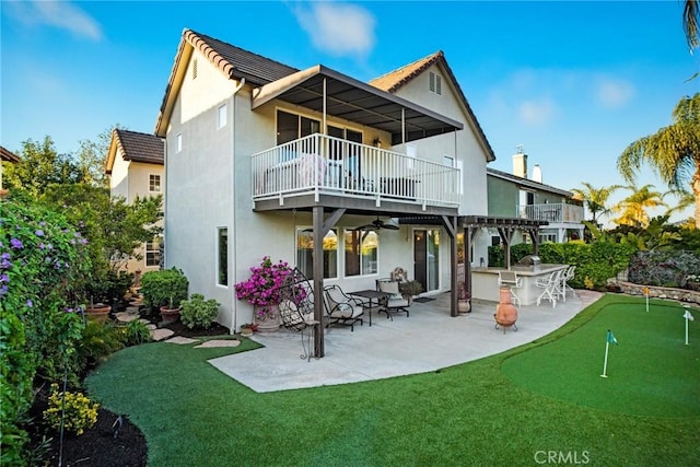 rear view of house featuring ceiling fan, outdoor dry bar, a patio area, a balcony, and stucco siding