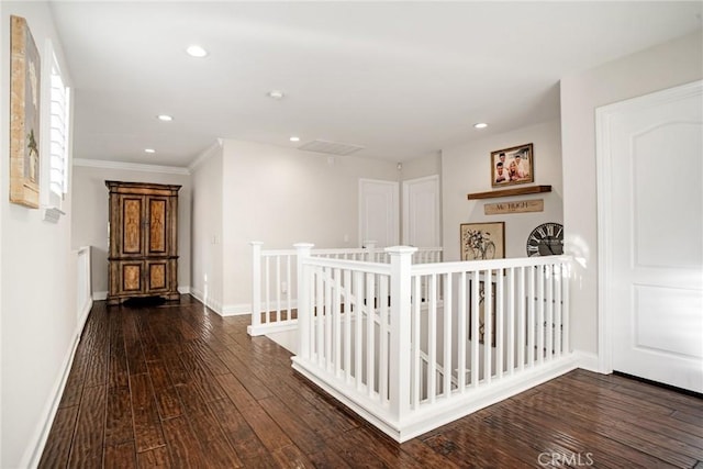hall with hardwood / wood-style flooring, baseboards, an upstairs landing, ornamental molding, and recessed lighting