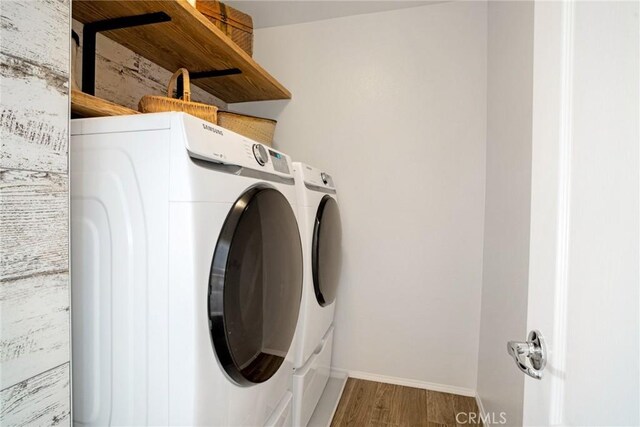 laundry area with laundry area, baseboards, wood finished floors, and washing machine and clothes dryer