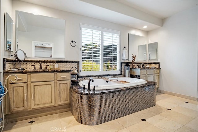 bathroom featuring a sink, tile patterned flooring, two vanities, tasteful backsplash, and a bath