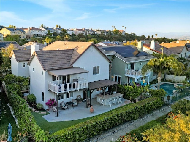 rear view of house featuring a chimney, a balcony, and a residential view