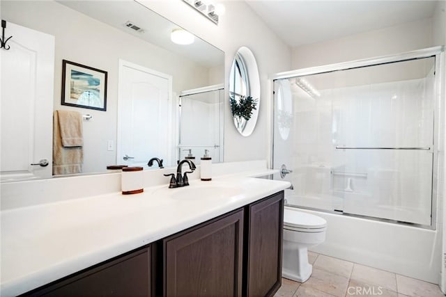 full bathroom featuring vanity, toilet, tile patterned floors, combined bath / shower with glass door, and visible vents