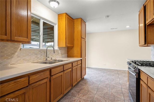 kitchen featuring a sink, light countertops, tasteful backsplash, and gas range