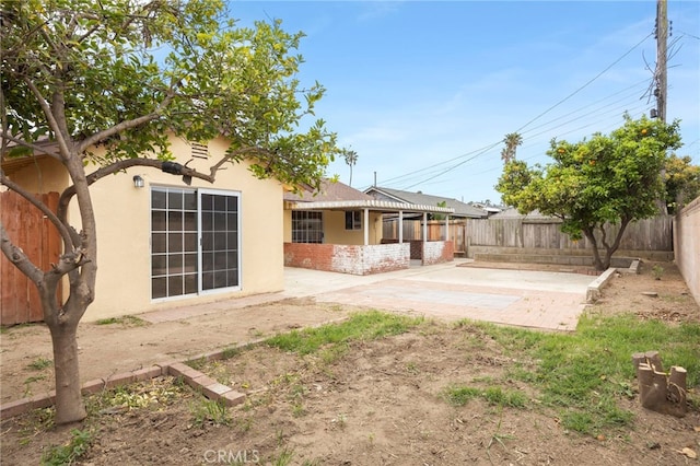 back of house with a fenced backyard, stucco siding, and a patio area