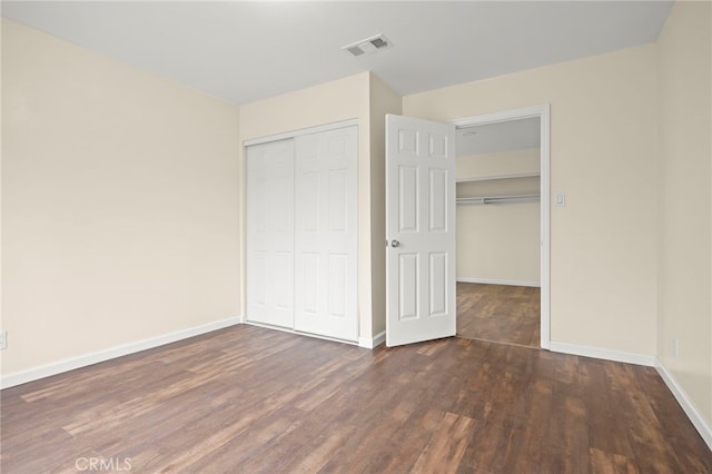 unfurnished bedroom featuring visible vents, baseboards, wood finished floors, and a closet