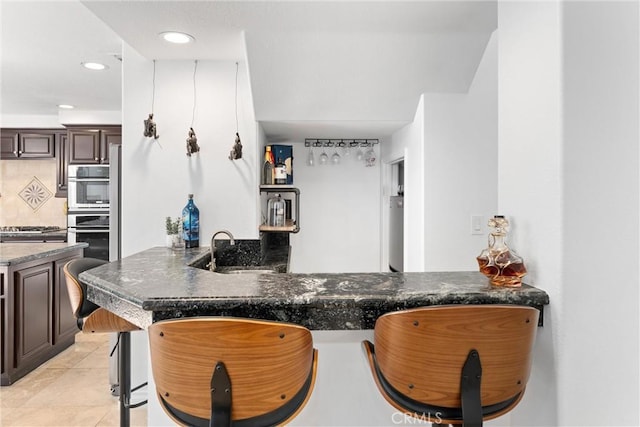 1720 San Alvarado Cir, Corona, CA 92882 - kitchen with a kitchen bar, dark brown cabinets, light tile patterned floors, a sink, and recessed lighting
