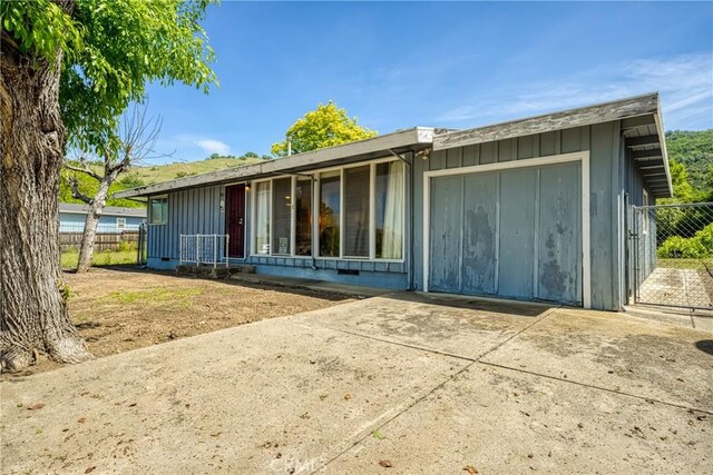 6828 Frontage Rd, Lucerne, CA 95458 - back of house featuring board and batten siding, fence, and concrete driveway