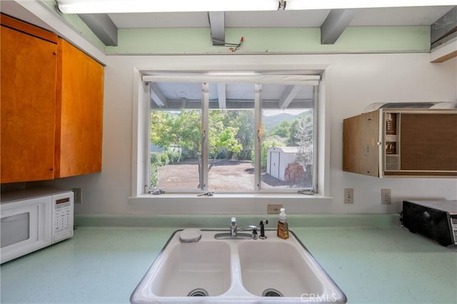 6828 Frontage Rd, Lucerne, CA 95458 - kitchen with light countertops, a sink, white microwave, and brown cabinets