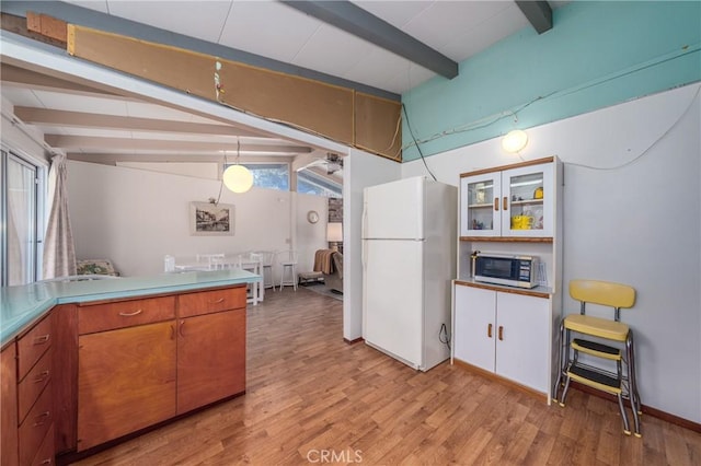 6828 Frontage Rd, Lucerne, CA 95458 - kitchen with brown cabinetry, freestanding refrigerator, light wood-style floors, vaulted ceiling with beams, and stainless steel microwave