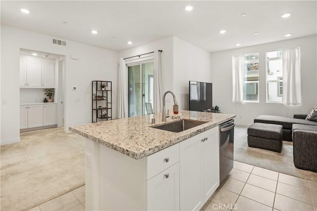 kitchen featuring visible vents, light colored carpet, stainless steel dishwasher, a sink, and open floor plan