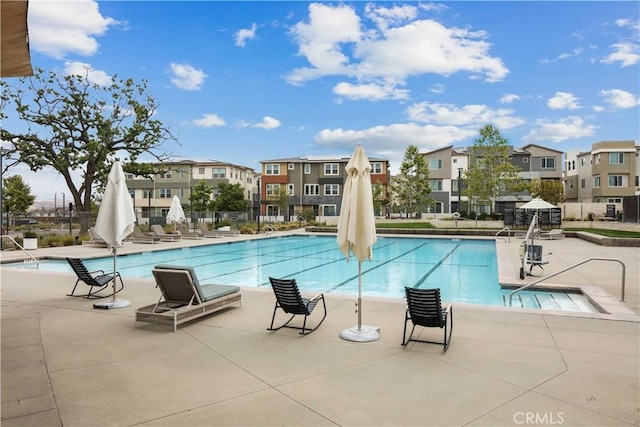 community pool with a patio, fence, and a residential view