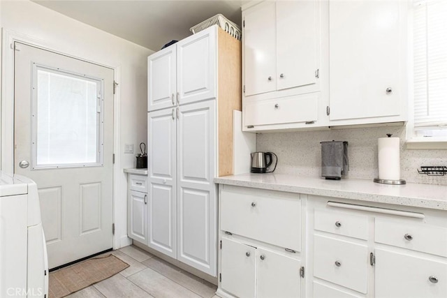 kitchen with white cabinets, light stone countertops, and washer / dryer