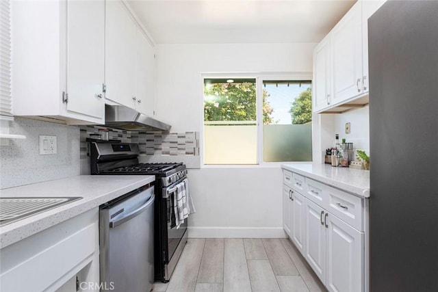 kitchen featuring appliances with stainless steel finishes, tasteful backsplash, light countertops, white cabinets, and under cabinet range hood