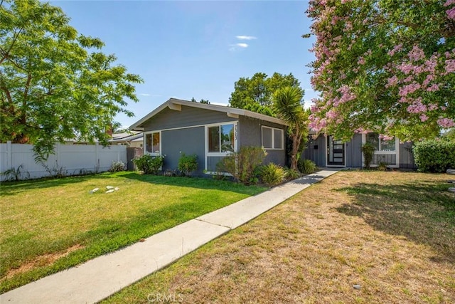 view of front facade with fence, stucco siding, and a front lawn