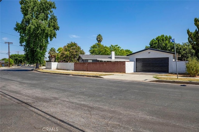exterior space with concrete driveway, an attached garage, fence, and stucco siding