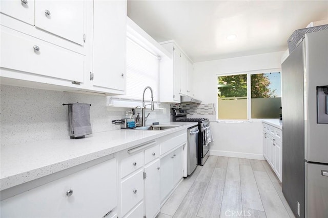 kitchen with white cabinets, appliances with stainless steel finishes, decorative backsplash, and a sink