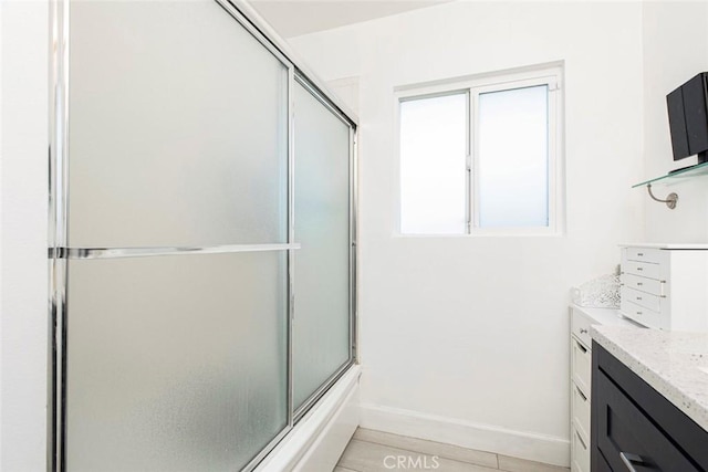 bathroom with baseboards, bath / shower combo with glass door, and vanity