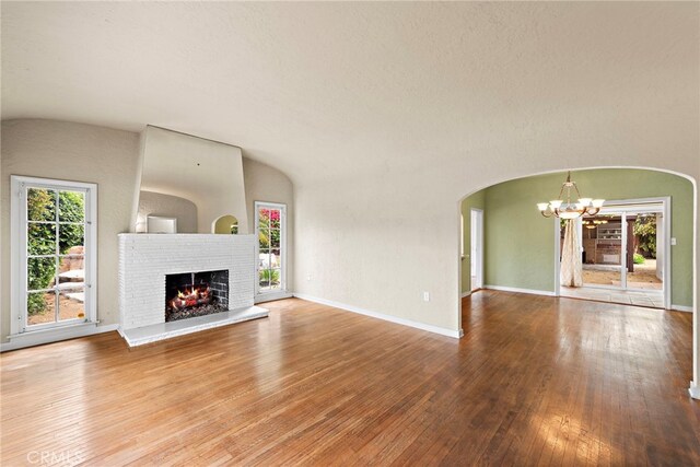 336 Marwood Ave, Fullerton, CA 92832 - unfurnished living room with a chandelier, wood-type flooring, a brick fireplace, arched walkways, and baseboards