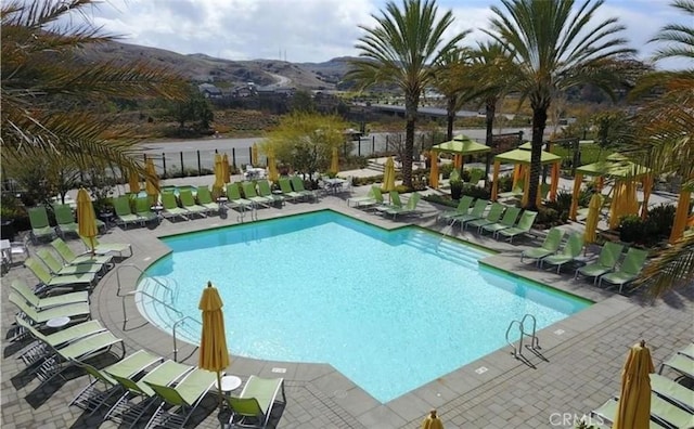 pool featuring a patio area, a mountain view, and fence
