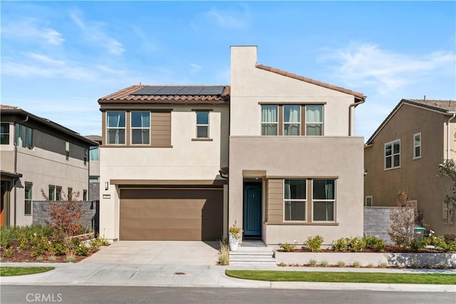 view of front of house featuring stucco siding, a tiled roof, an attached garage, driveway, and solar panels