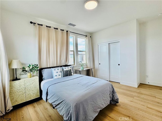 bedroom with light wood-style floors, baseboards, a closet, and visible vents