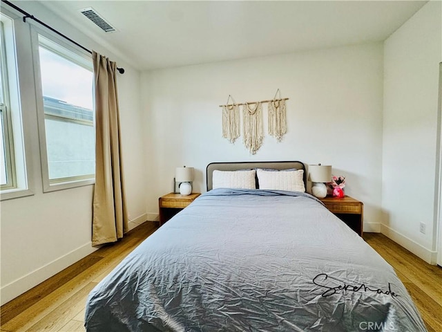 bedroom with baseboards, wood finished floors, and visible vents