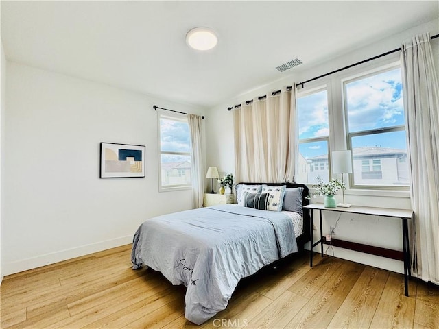 bedroom with light wood-type flooring, baseboards, and visible vents