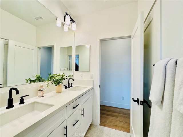 bathroom featuring double vanity, a sink, baseboards, and wood finished floors