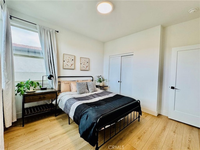 bedroom with baseboards, light wood-style flooring, and a closet