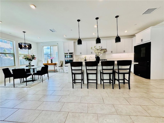 kitchen with recessed lighting, a breakfast bar area, stainless steel double oven, and visible vents