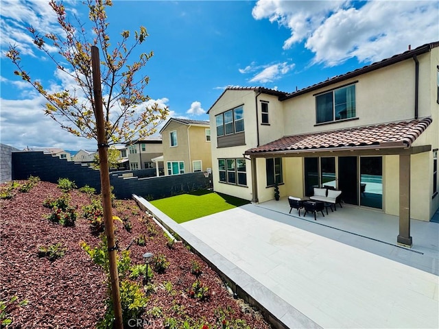rear view of property featuring a tiled roof, a fenced backyard, a patio area, and stucco siding
