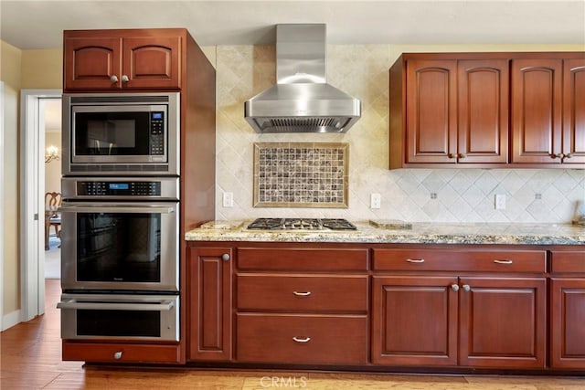 kitchen with tasteful backsplash, stainless steel appliances, light wood-type flooring, and island range hood