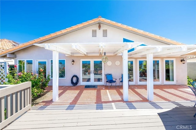 back of house with french doors, stucco siding, a pergola, and a wooden deck