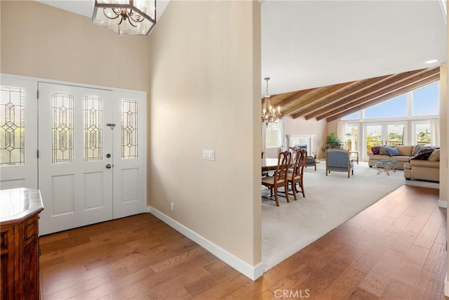foyer featuring beam ceiling, wood finished floors, high vaulted ceiling, baseboards, and a notable chandelier