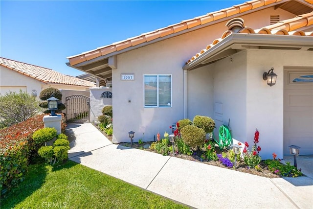 property entrance featuring a tiled roof, a gate, and stucco siding