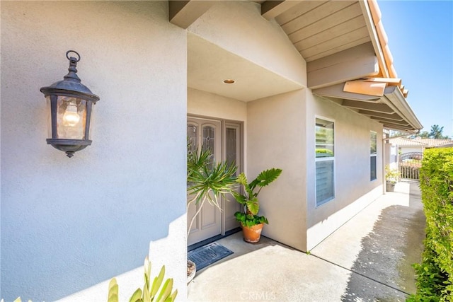 property entrance featuring fence and stucco siding