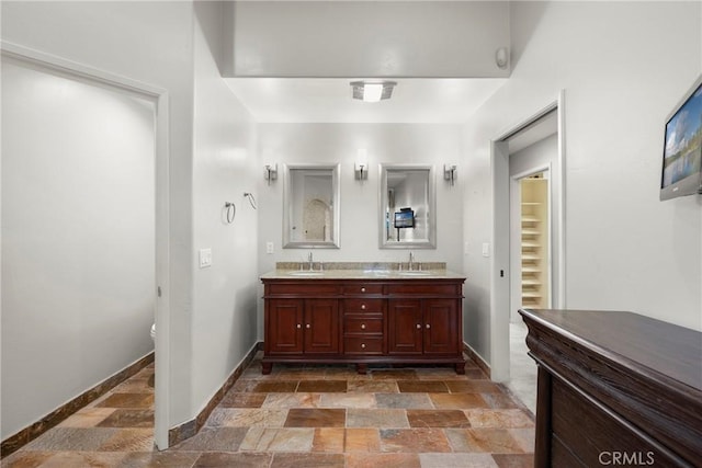 bathroom with baseboards, a sink, and stone tile floors