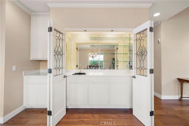bar featuring crown molding, an inviting chandelier, dark wood finished floors, recessed lighting, and baseboards