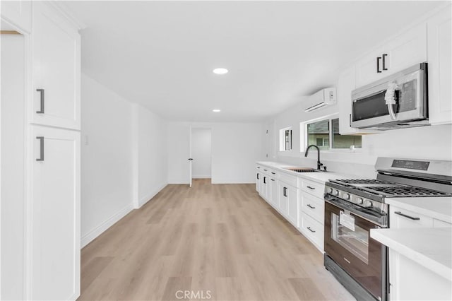 7307 Diamond St, Riverside, CA 92504 - kitchen with a sink, light wood-type flooring, light countertops, a wall unit AC, and appliances with stainless steel finishes