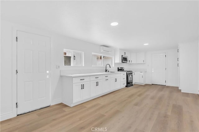 7307 Diamond St, Riverside, CA 92504 - kitchen with stainless steel appliances, an AC wall unit, light wood finished floors, a sink, and light countertops