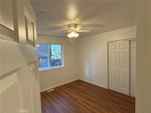 spare room featuring visible vents, baseboards, ceiling fan, and dark wood-style floors