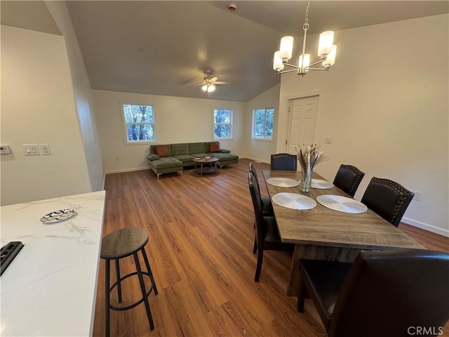 dining area featuring baseboards, vaulted ceiling, and wood finished floors