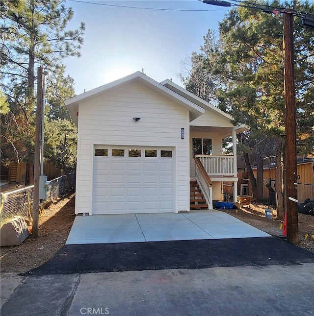 view of front of property with a garage, covered porch, stairway, and aphalt driveway