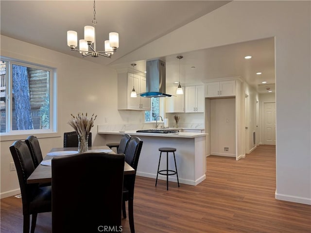 dining area featuring vaulted ceiling, wood finished floors, baseboards, a chandelier, and recessed lighting