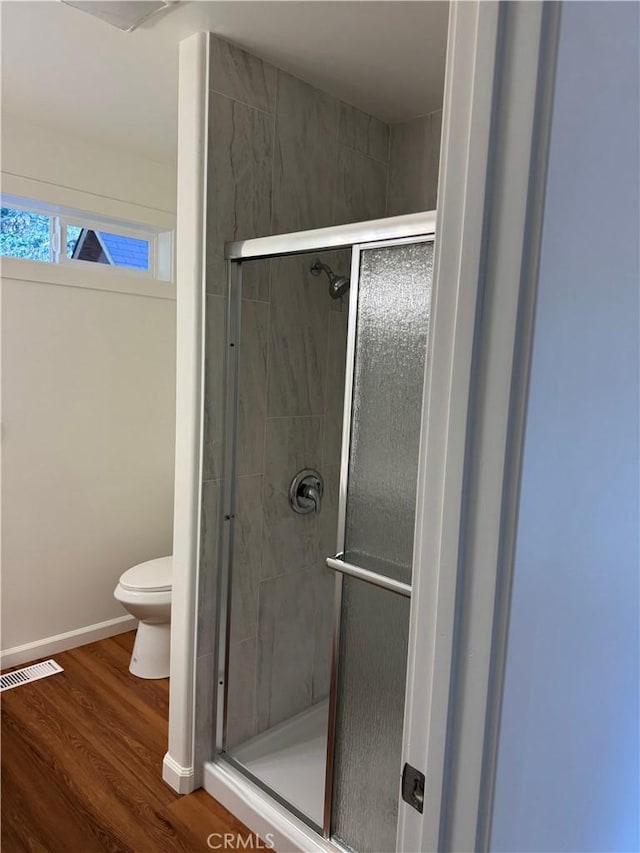 full bath featuring a shower stall, toilet, wood finished floors, and visible vents