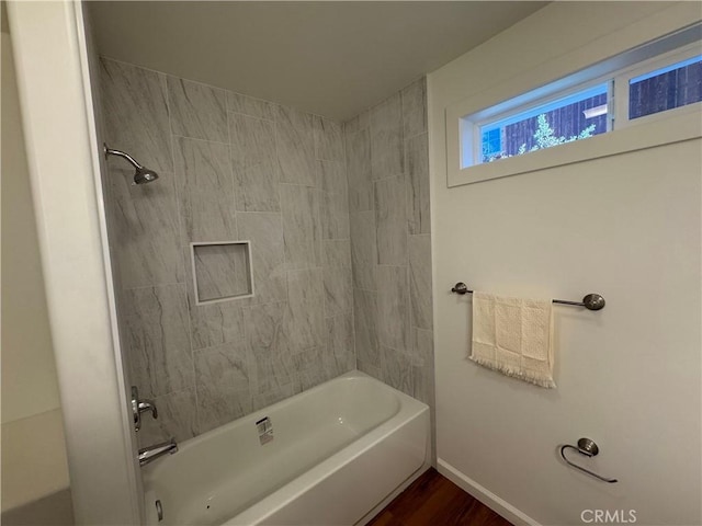bathroom with baseboards, shower / bathing tub combination, and wood finished floors