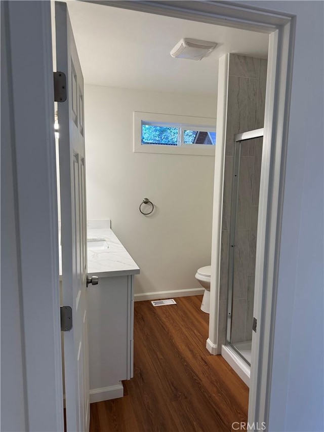 full bath featuring a shower stall, toilet, wood finished floors, and visible vents
